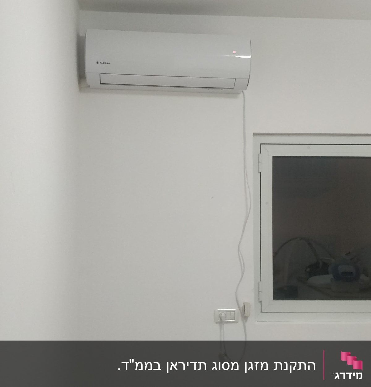 מזגן מותקן על קיר לבן עם כבל חשמל